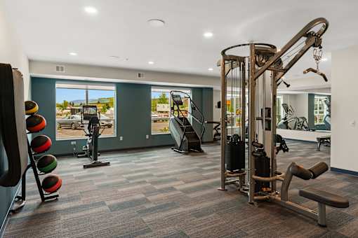 A gym with a variety of equipment including a leg press machine, a chest press machine, and a squat rack at The Beaumont Apartments, Montana