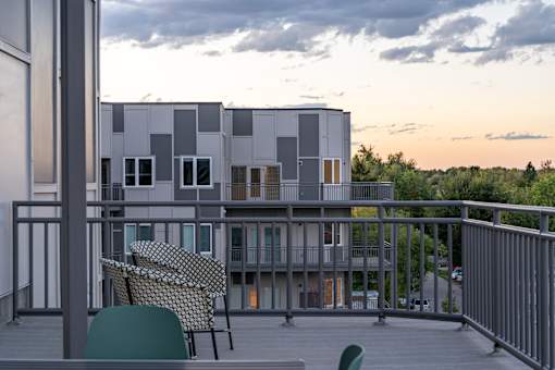 A modern building with a balcony and chairs.at Copestone Apartments, Garden City, ID 59808