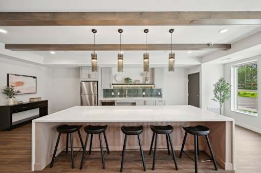 A modern kitchen with a bar area and black stools.