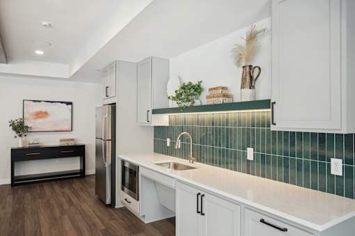 A kitchen with white cabinets and a green backsplash.