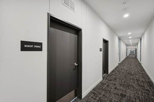 A hallway with a black door and a sign that says "Resident Storage".