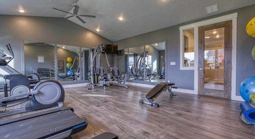 a gym with weights and cardio equipment and a glass door