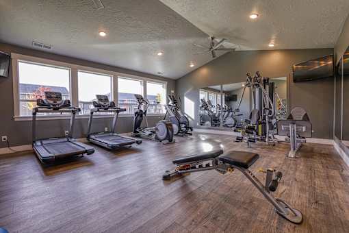 a gym with exercise equipment and windows with a view