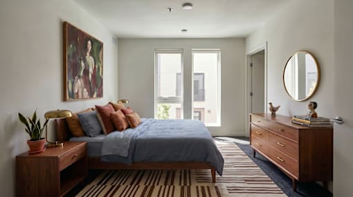 A bedroom with a bed, dresser, and a painting on the wall at The Clara in Eagle, ID 83616