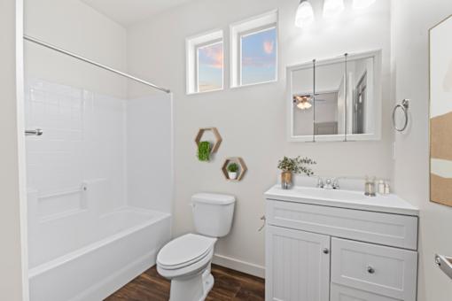 A white bathroom with a toilet, sink, and bathtub. at Verraso Village Apartments, Idaho