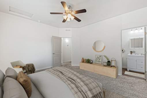 A bedroom with a bed, a couch, a ceiling fan, and a dresser. at Verraso Village Apartments, Meridian
