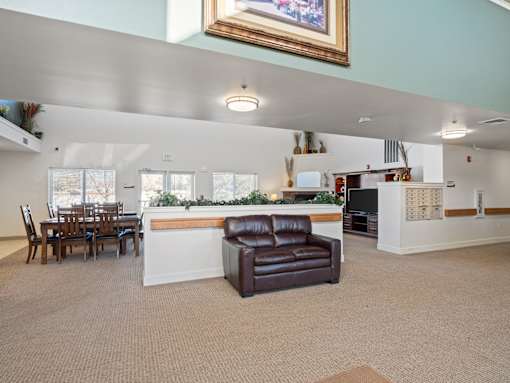 A living room with a brown leather couch and a dining table with chairs.