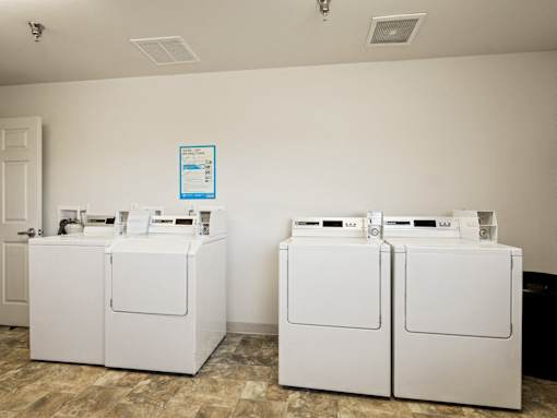 Two white front loading washing machines in a laundry room.