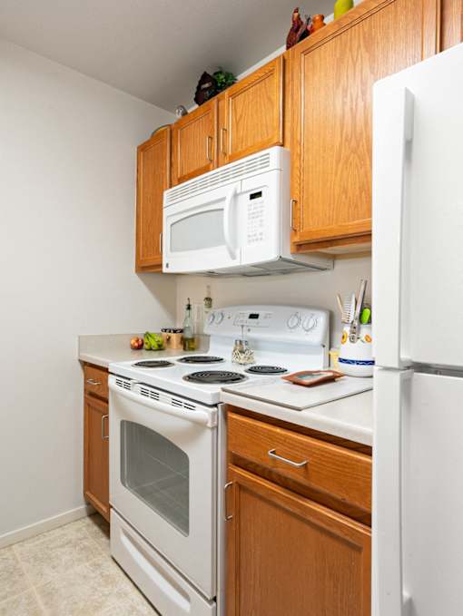 A white microwave is mounted above a white stove in a kitchen.