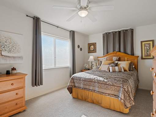 A bedroom with a large bed and a ceiling fan.