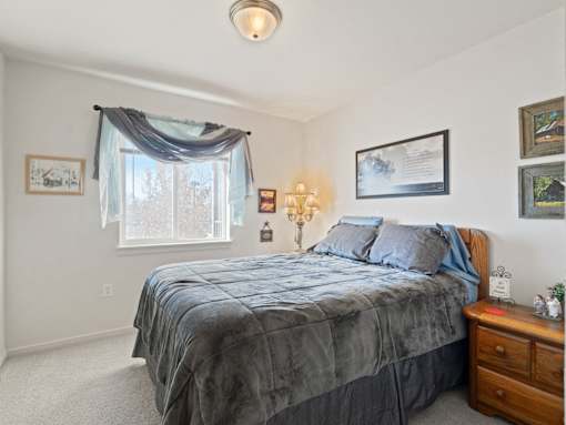 A bedroom with a bed, nightstand, and pictures on the wall.