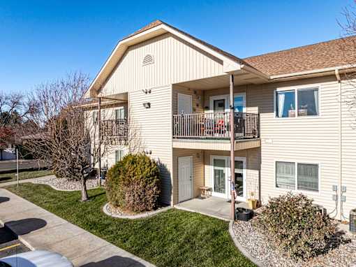 A beige two-story apartment building with a balcony on the second floor.