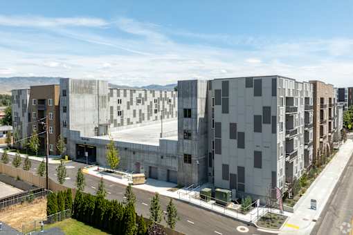 A modern building complex with a parking lot in front.