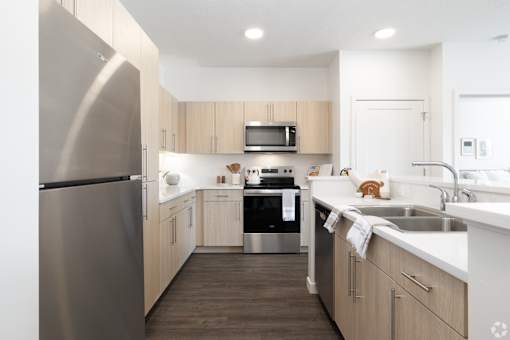 A modern kitchen with a stainless steel refrigerator and wooden cabinets.