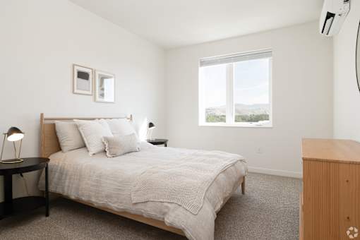 A bedroom with a bed, nightstand, and window.