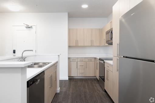 A kitchen with a stainless steel refrigerator and wooden cabinets.