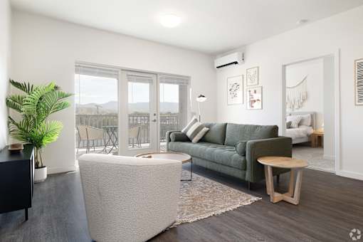 A living room with a green couch and a white ottoman.