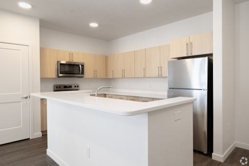 A kitchen with white countertops and a stainless steel refrigerator.