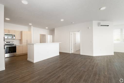 A spacious kitchen with wooden floors and white walls.