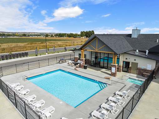A large outdoor swimming pool surrounded by a fence and lounge chairs at The Expo in Billings, MT,
