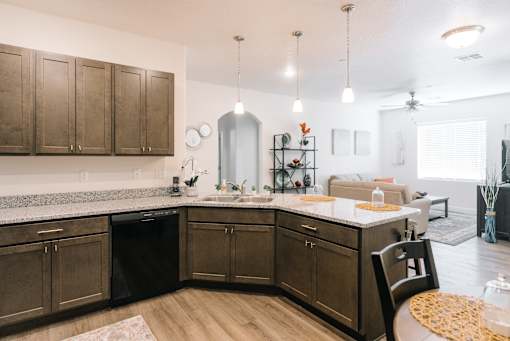 A kitchen with dark brown cabinets and a black dishwasher.