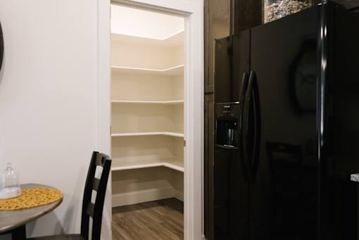 A black refrigerator is in a kitchen with a table and a chair.