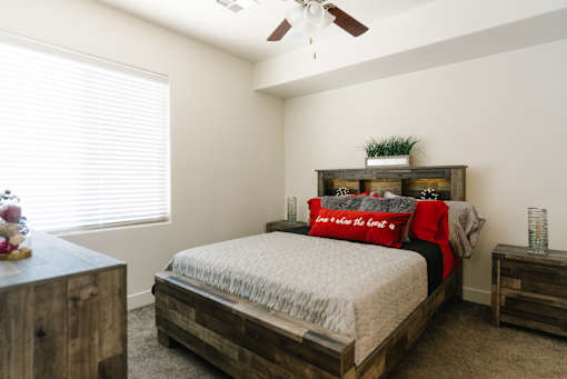 A bedroom with a bed, nightstand, and a ceiling fan.