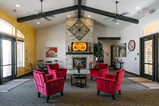 A living room with a fireplace and red chairs.