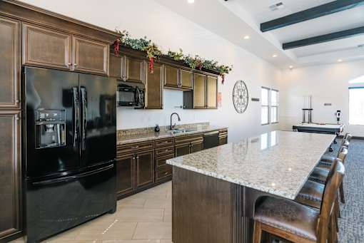 A kitchen with a black refrigerator and brown cabinets.