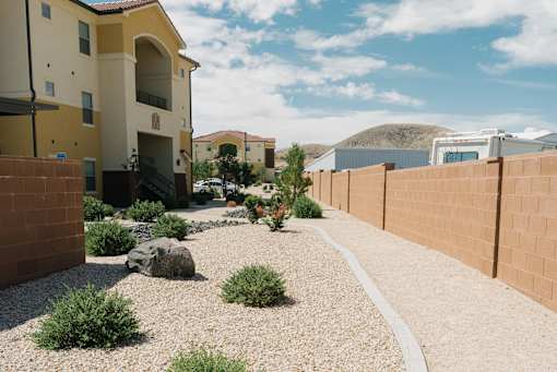 A small garden with a gravel path and a few plants in front of a building.