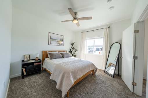 A bedroom with a bed, nightstand, and a ceiling fan. at Silverbrook Apartments, Montana, 59901