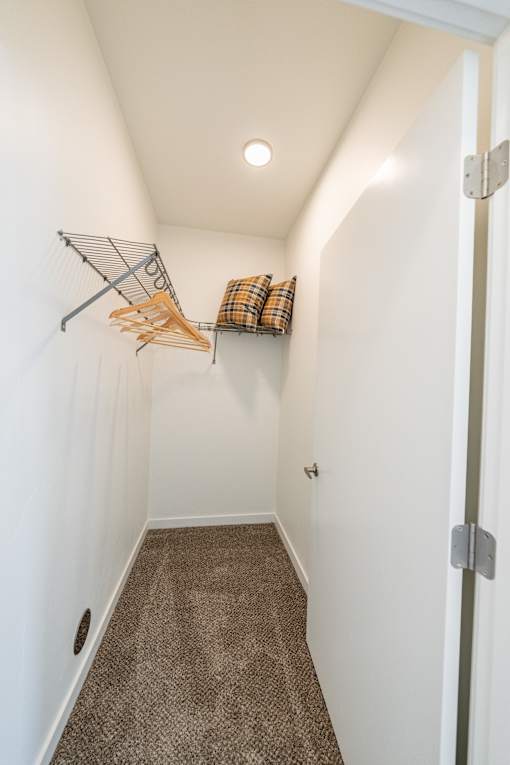 A hallway with a brown carpet and a white wall. at Silverbrook Apartments, Kalispell 59901