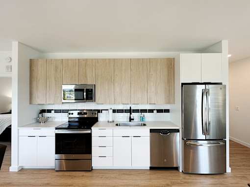 A modern kitchen with a stainless steel refrigerator, oven, and sink.