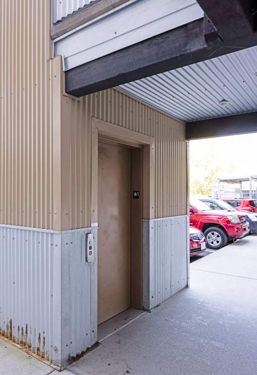 A brown door is open to a parking lot.
