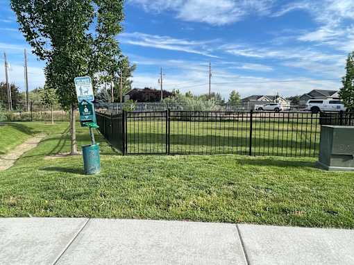 a park with a fence and a sign in the grass