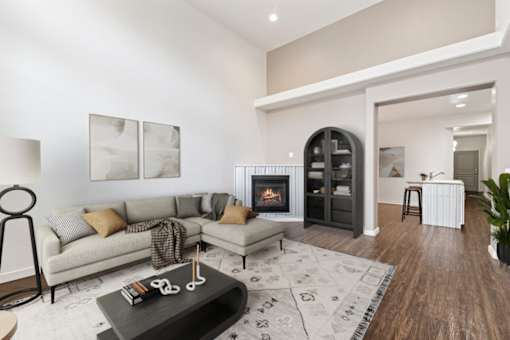A modern living room with a fireplace and a grey sofa. at Verraso Village Apartments, Meridian, ID