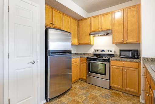 A kitchen with wooden cabinets and a stainless steel refrigerator.