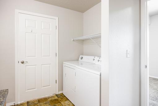 A white door is on the left of a white washing machine.
