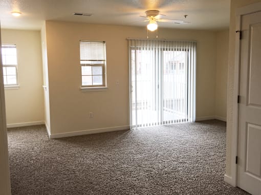 A room with a carpeted floor and a ceiling fan.