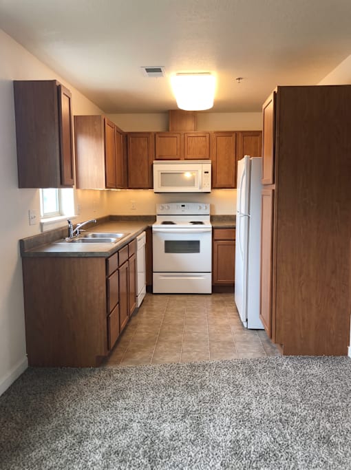 A kitchen with a white refrigerator and wooden cabinets.