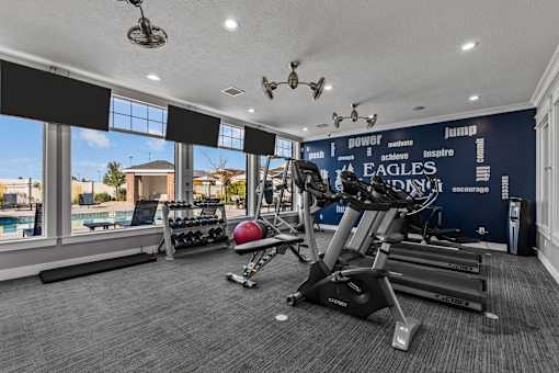 Resident Fitness Center with natural light and a wall of windows overlooking the pool at Eagles Landing Apartments, Ammon, ID