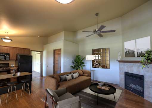 A living room with a couch, a coffee table, a fireplace, and a ceiling fan.