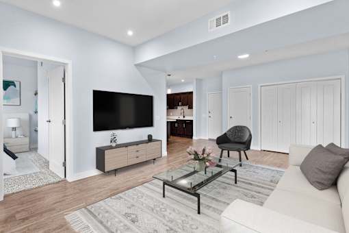 A modern living room with a white couch, a black chair, and a glass coffee table.