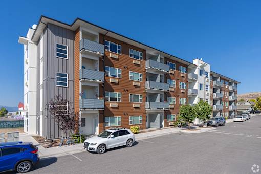 A modern apartment building with cars parked in front.