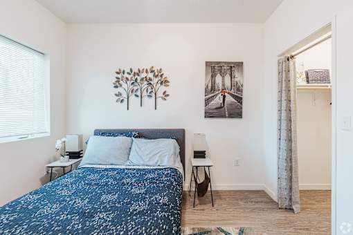 A bedroom with a bed, nightstands, and a painting on the wall.