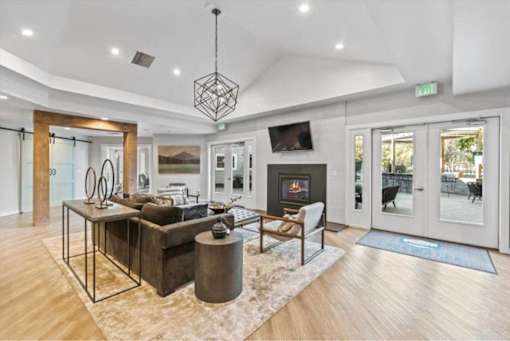 Modern living room with geometric chandelier and fireplace at Edgewater Apartments, Idaho