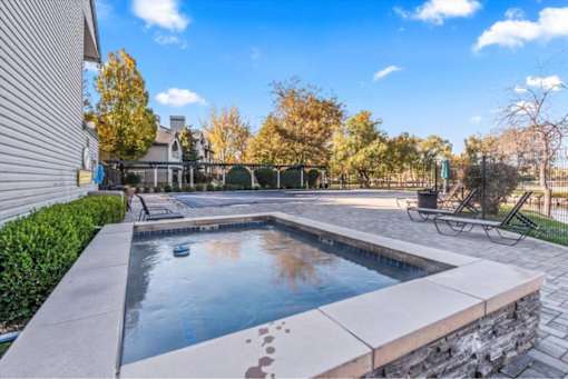Raised spa with stone coping and lounge chairs at Edgewater Apartments, Idaho