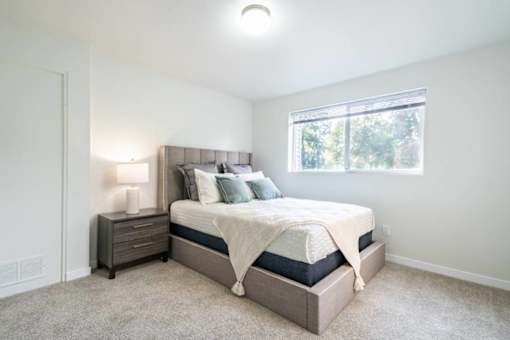 Modern bedroom with gray upholstered headboard at Edgewater Apartments, Boise