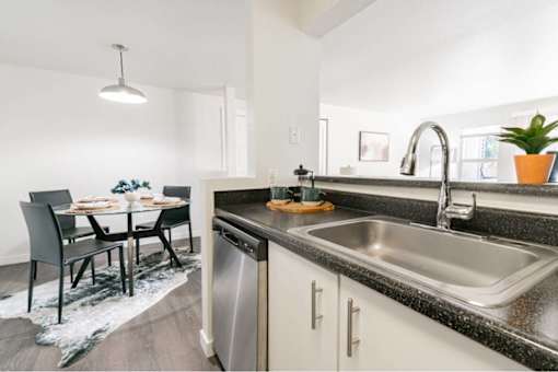 Modern kitchen with granite countertops and dining area at Edgewater Apartments, Boise, ID