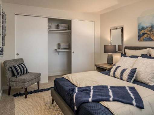 Bedroom with open closet and accent chair at Edgewater Apartments, Boise